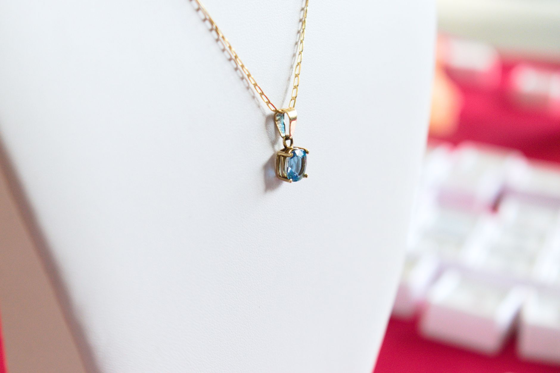 Collier délicat avec pendentif saphir bleu sur chaîne dorée sur mannequin blanc