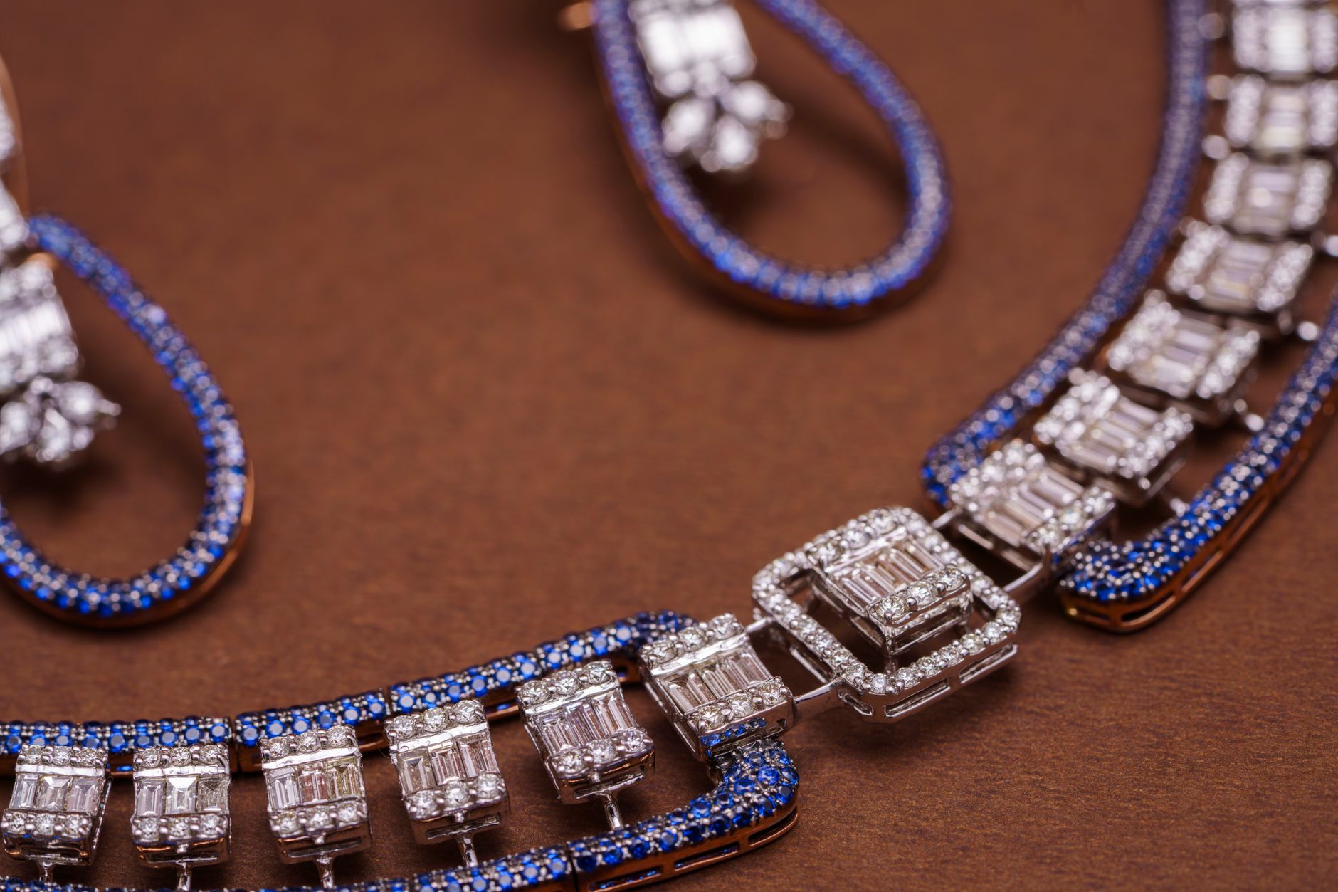 Bracelets en or blanc ornés de diamants taille baguette et de saphirs bleus sur fond marron